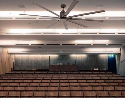 Grand écran et salle de conférence; plafond avec grand ventilateur et rangées de sièges en auditorium, ambiance pédagogique. comment calculer un déstratificateur intégrée naturellement.