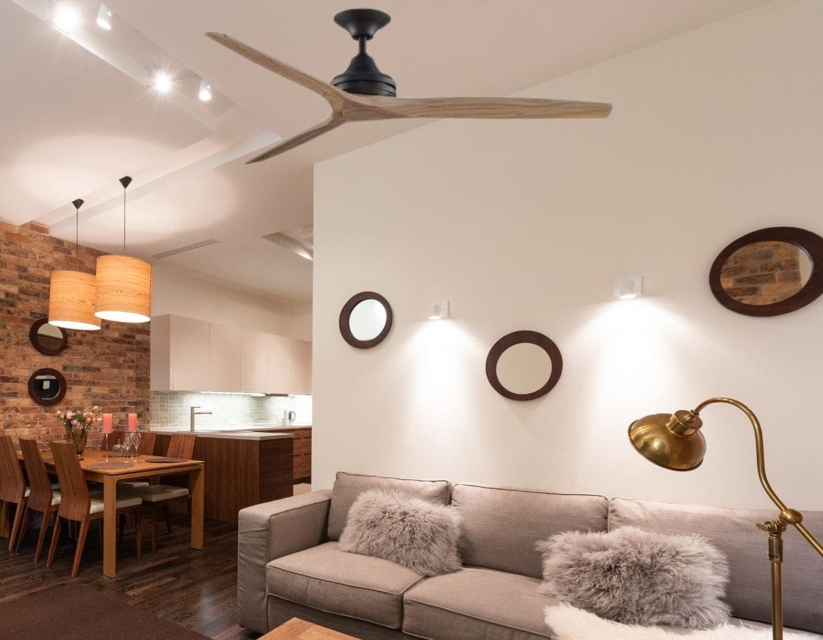 Comment installer un ventilateur de plafond dans un séjour moderne avec canapé et lampe de bureau, vue d’ensemble sur le plafonnier et le coin repas.
