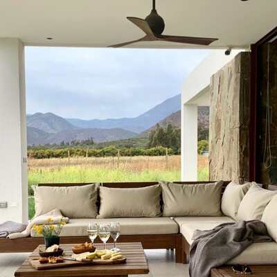 Salon extérieur confortable avec canapé et table basse surplombant un paysage de campagne et montagnes au loin.