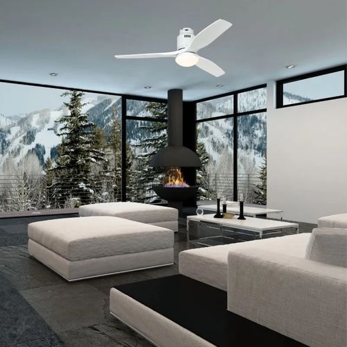 Salle de séjour moderne avec canapé clair et cheminée, vue sur montagne par de grandes fenêtres, ventilateur au plafond.