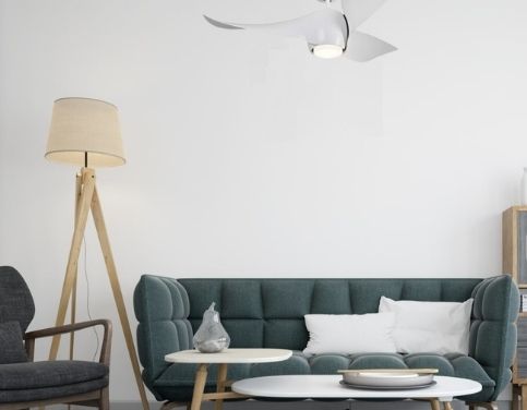 Salon cozy avec canapé vert, table basse blanche et chaise, éclairé par lampe sur pied et une lampe suspendue au plafond.