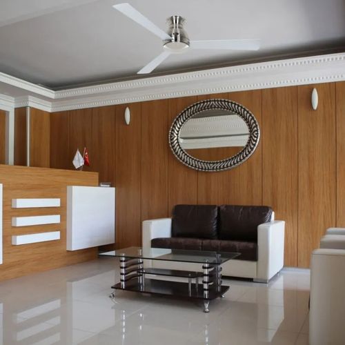 Un salon moderne avec un canapé blanc et noir, une table basse en verre et bois, et un ventilateur de plafond blanc.