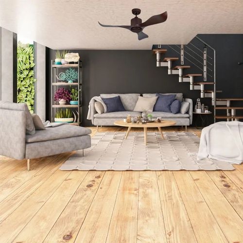 Salon moderne avec canapé et fauteuils autour d'une table basse, sous un ventilateur de plafond suspendu.