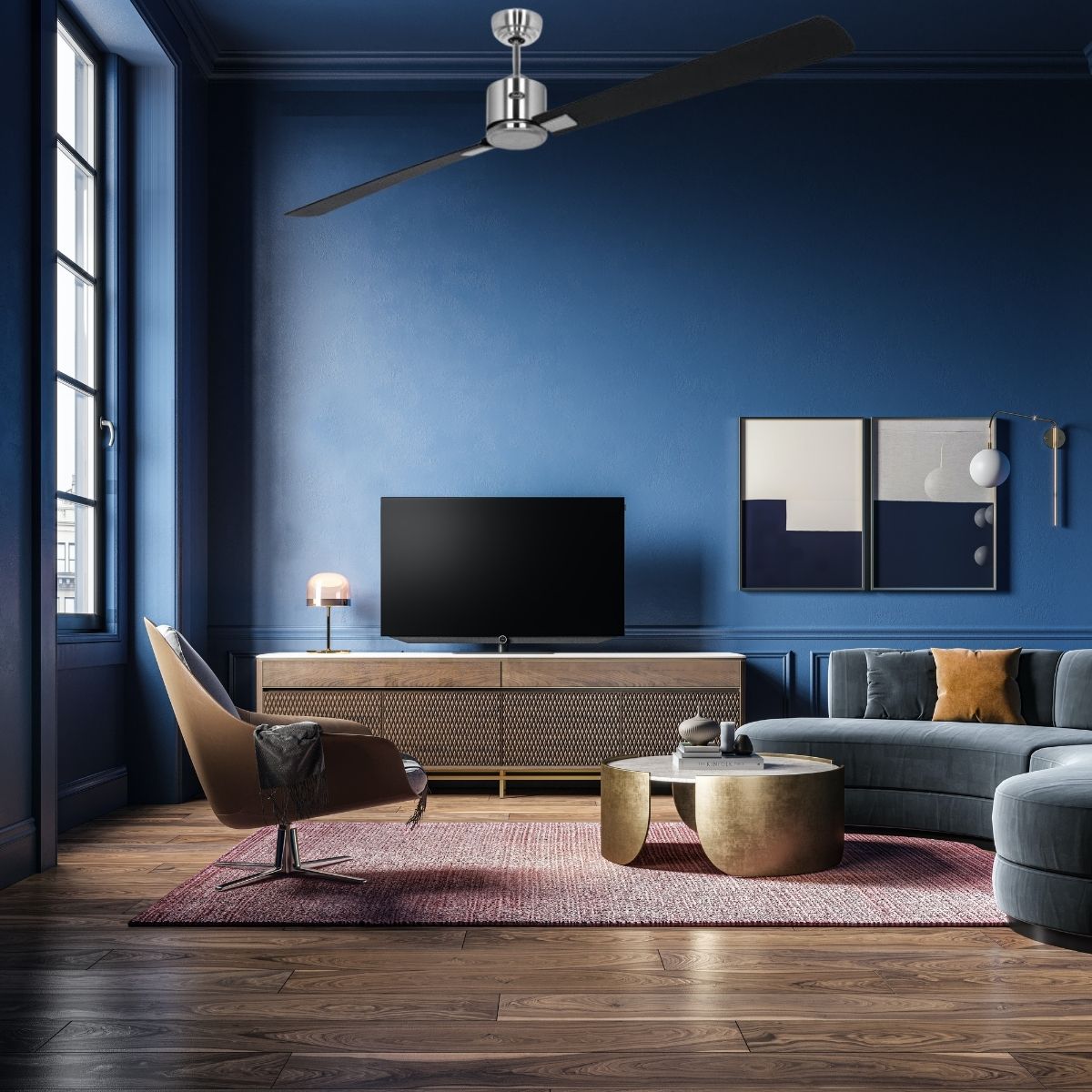 Ventilateur de plafond moderne au-dessus d’un salon bleu avec canapé et table basse dorée vue de côté.