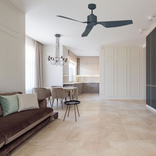 Vue d’un salon lumineux avec canapé, fauteuils et table basse, ouvert sur une cuisine moderne en arrière-plan.